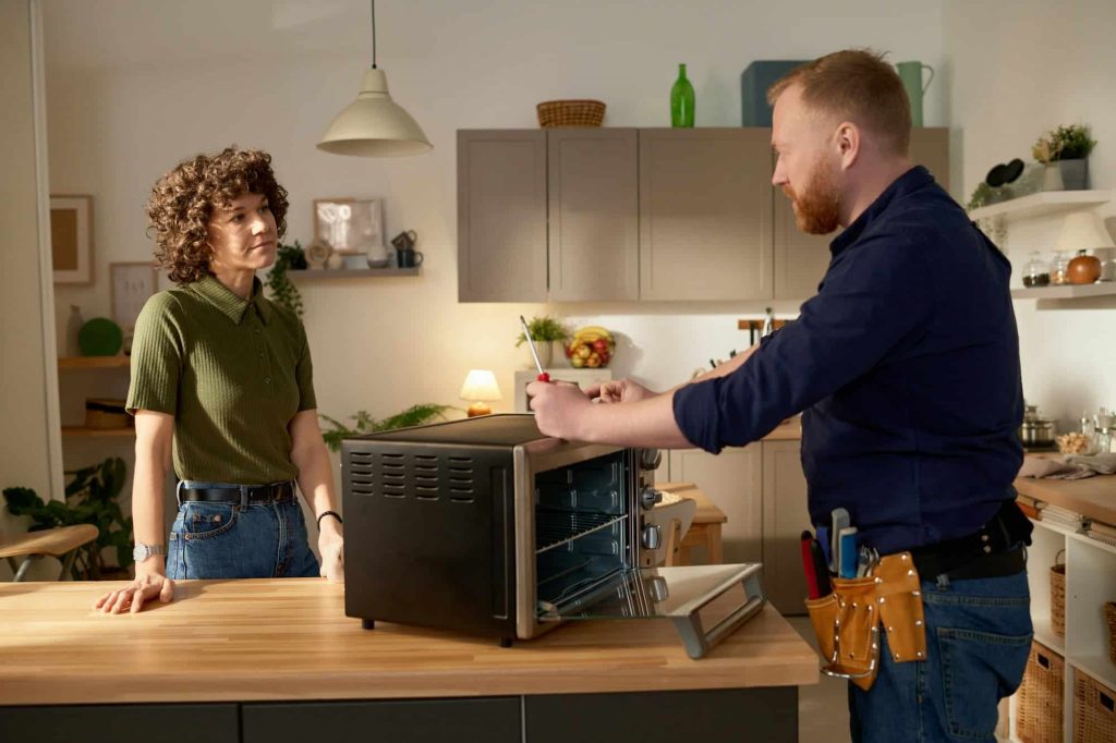 man repairing broken microwave at home