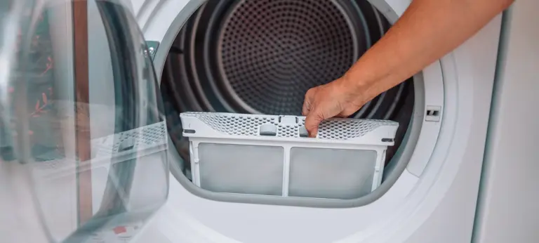 Housewife cleanup lints and dirt from tumble dryer filter. Clothes dryer lint filter that is covered with lint. Taking the lint out from dirty air filter of the dryer machine before use the machine.