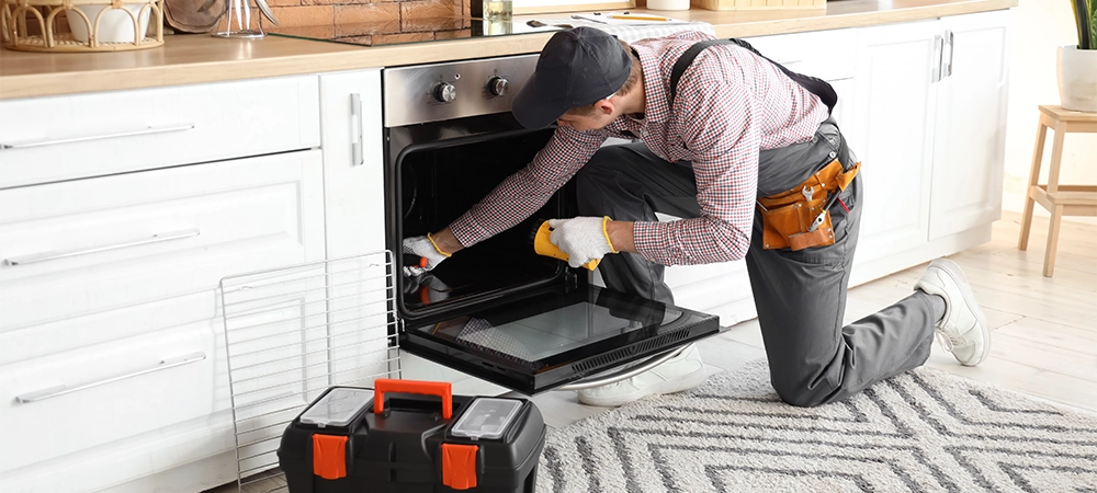 oven troubleshooting fixes Male technician repairing electric oven in kitchen