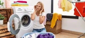 Young caucasian woman doing laundry with clothes in the basket covering ears with fingers with annoyed expression for the noise of loud music. deaf concept.