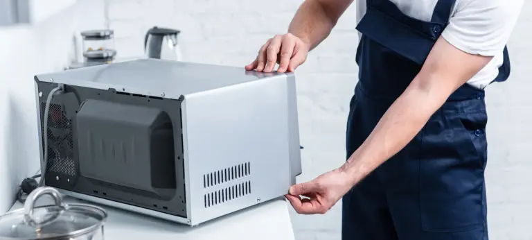 partial view of adult handyman repairing microwave oven in kitchen