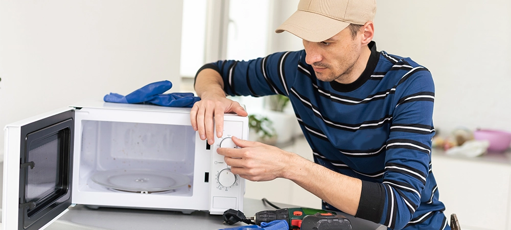 man repairing microwave. a worker repairs a microwave oven.