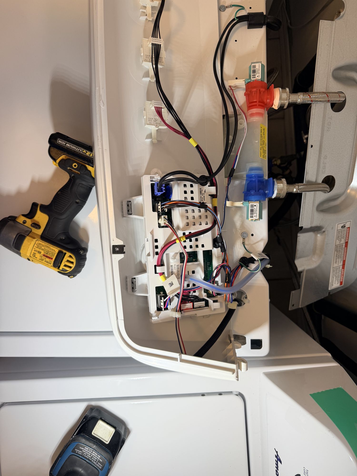 Samsung front-load washer pulled 6 inches away from the laundry-room wall with the back hose connections visible