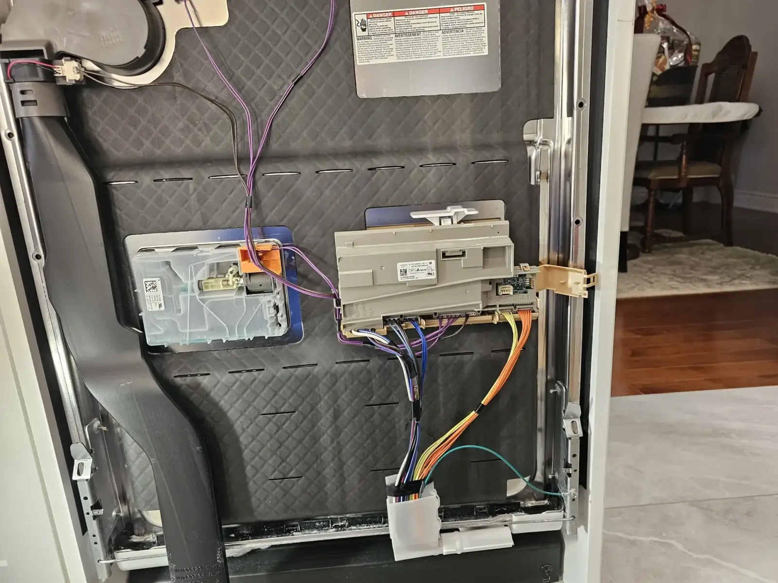 Back panel of an appliance opened during an in-home repair visit, with internal components exposed