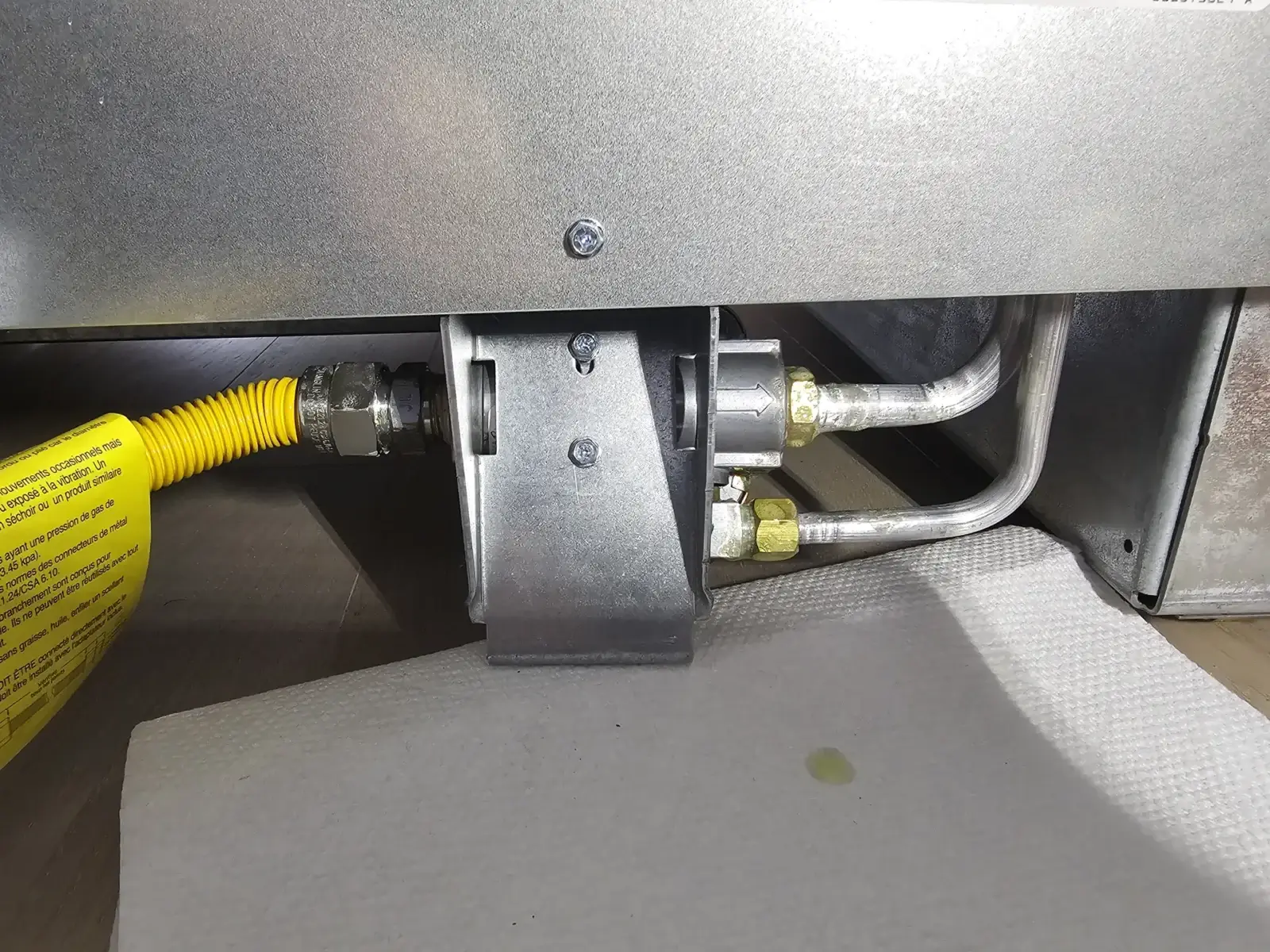appliance repair close up metal gas connections pipes beneath appliance bradford