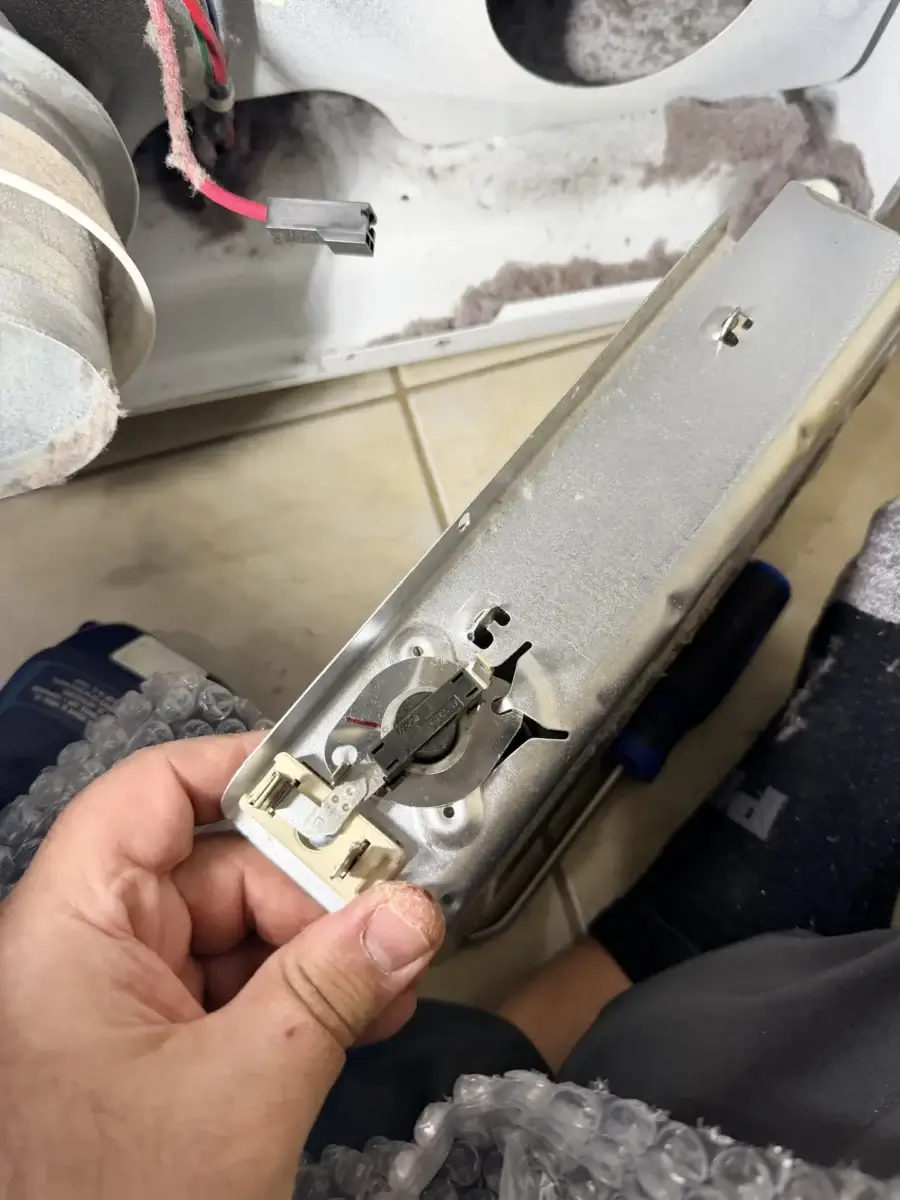 appliance repair hand holds metal appliance part electrical connectors broken he