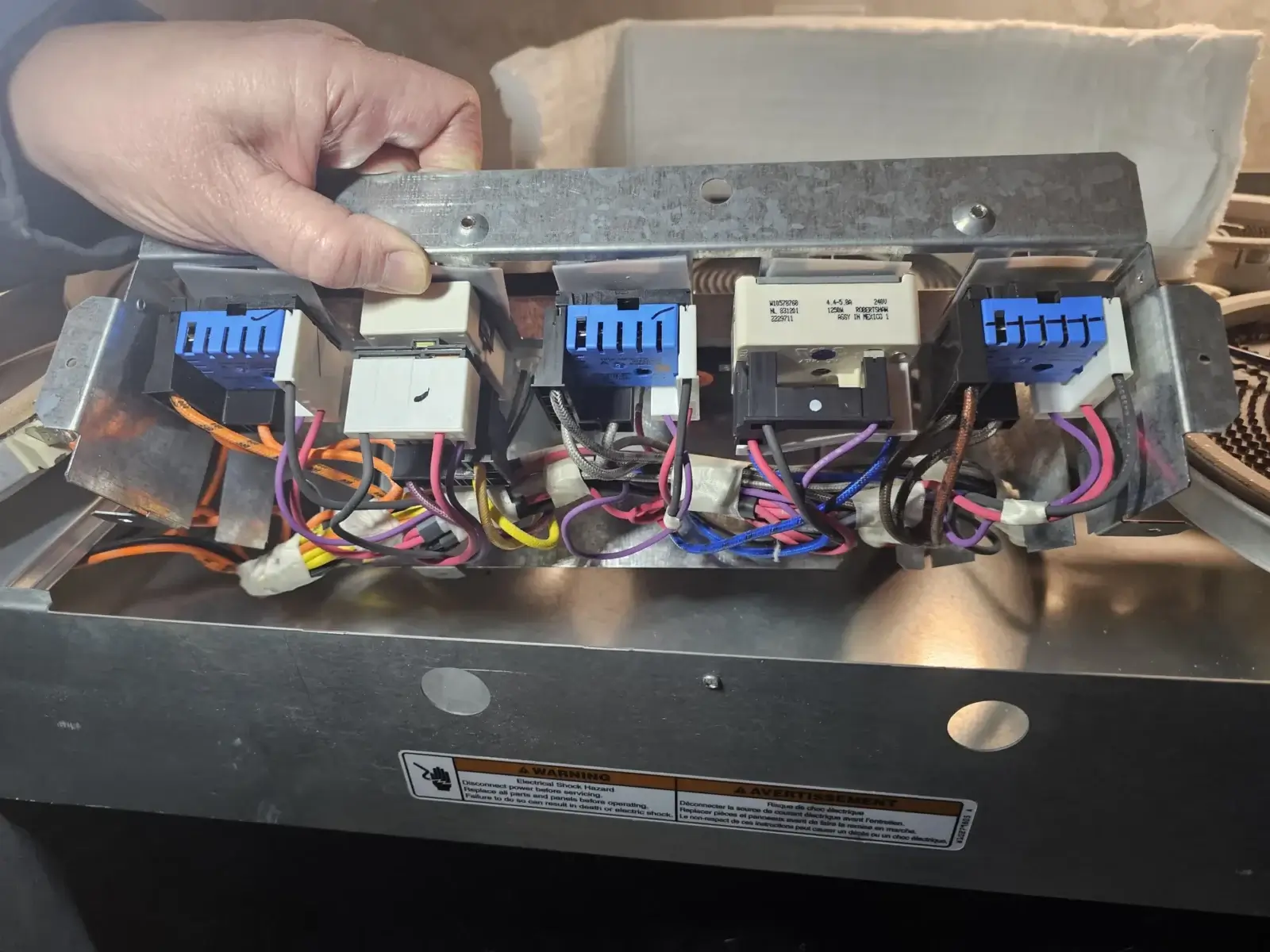 appliance repair person holds metal panel multiple electrical relays colorful wi