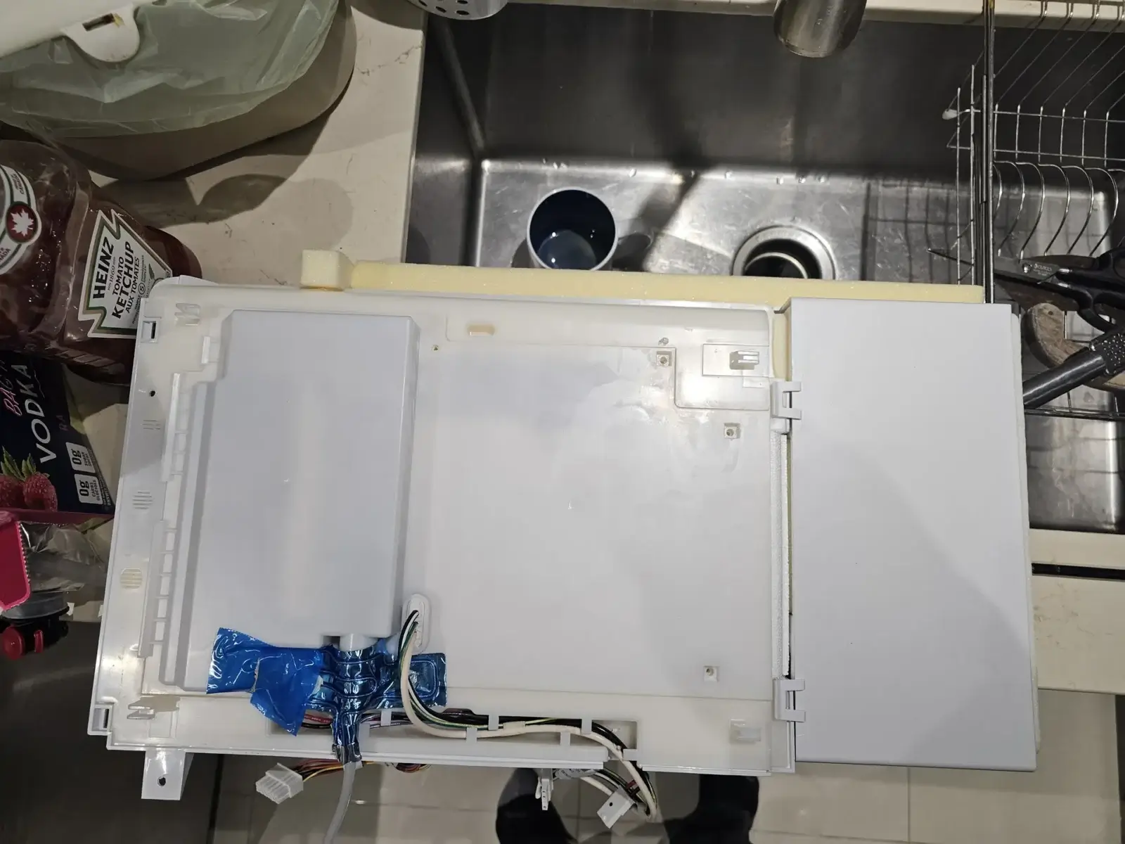 appliance repair white plastic appliance part wires blue tape sits kitchen count
