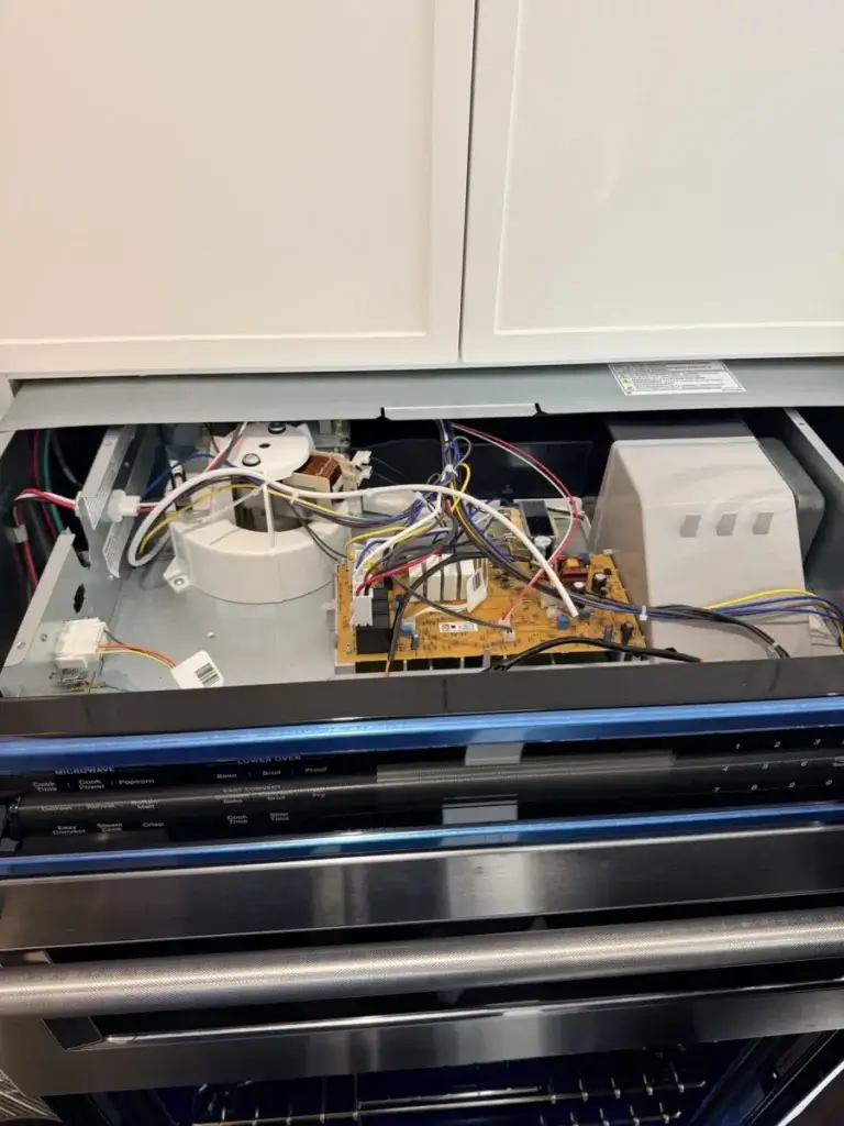 Built-in microwave and wall oven with the top panel open during a service visit