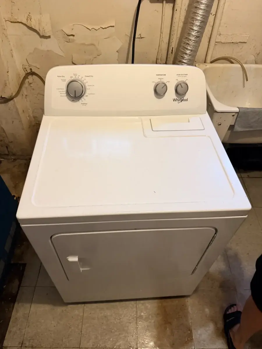 White Whirlpool clothes dryer in a GTA basement laundry area &mdash; the typical machine behind a dryer repair cost question