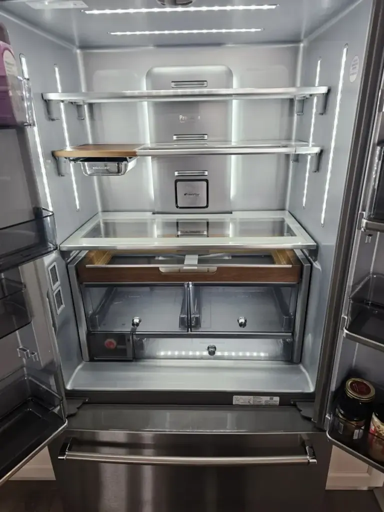 Empty stainless steel refrigerator interior with LED lighting after a repair visit