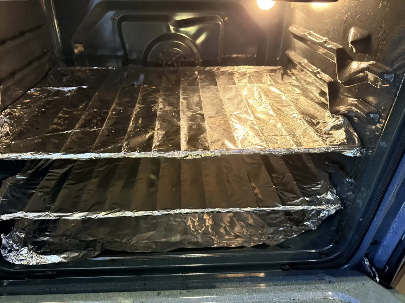 oven repair two oven racks covered crinkled aluminum foil inside oven oven light
