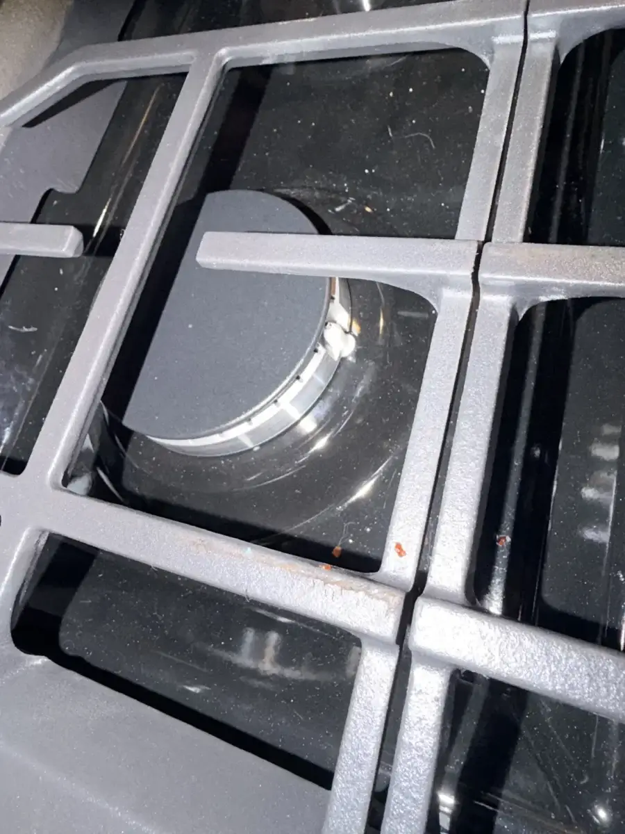 Close-up of a black gas stove burner and metal grates
