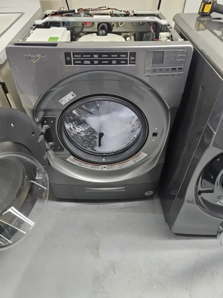 Front-load washer with soapy water sitting in the drum, the classic symptom of a drain fault