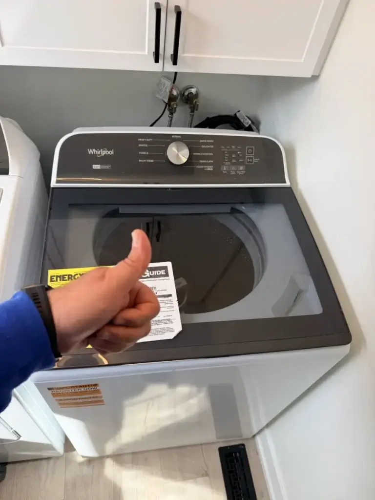 Technician giving a thumbs-up in front of a repaired top-load washer
