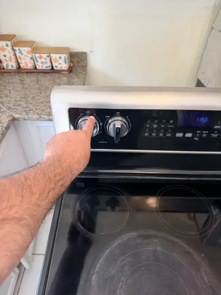 Appliance Forever technician pointing out the control knobs on a stainless steel range during a Vaughan service call