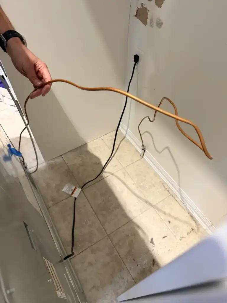 Appliance Forever technician holding a damaged copper appliance supply line removed during a GTA installation