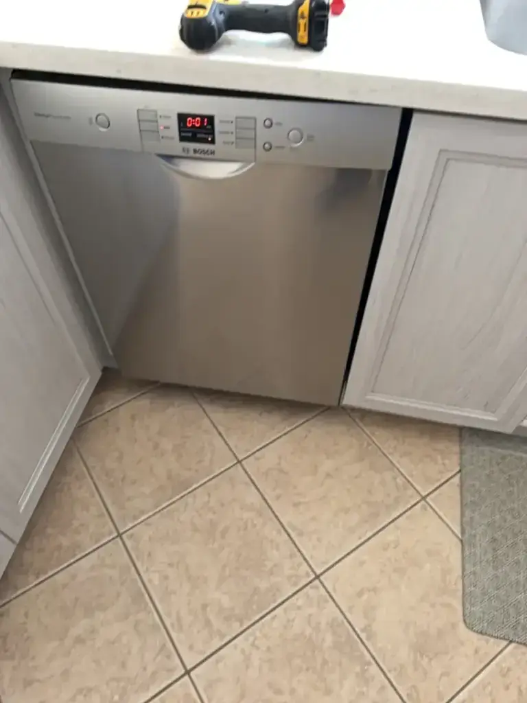 Bosch dishwasher freshly installed under the counter, the installer's drill still on the countertop