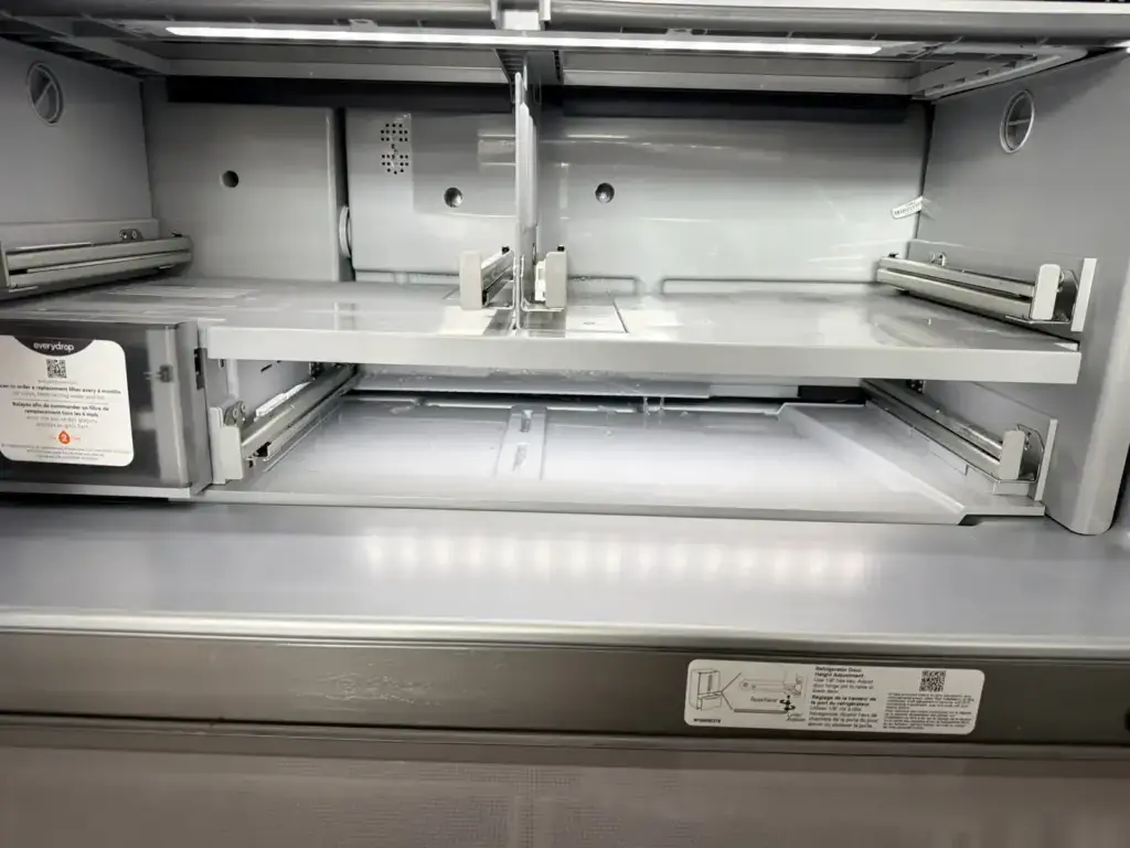 Refrigerator interior shelf supports with the EveryDrop water filter housing visible