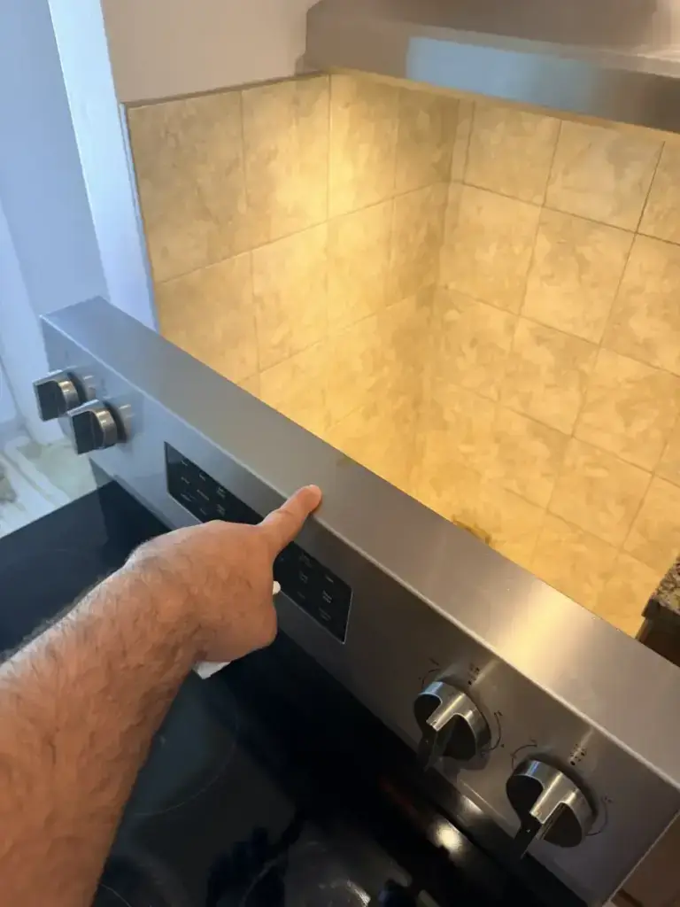 stove repair appliance forever technician pointing stainless control panel slide