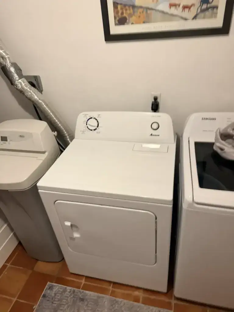 Amana dryer between a water softener and a Samsung top-load washer in a Bradford-area laundry room