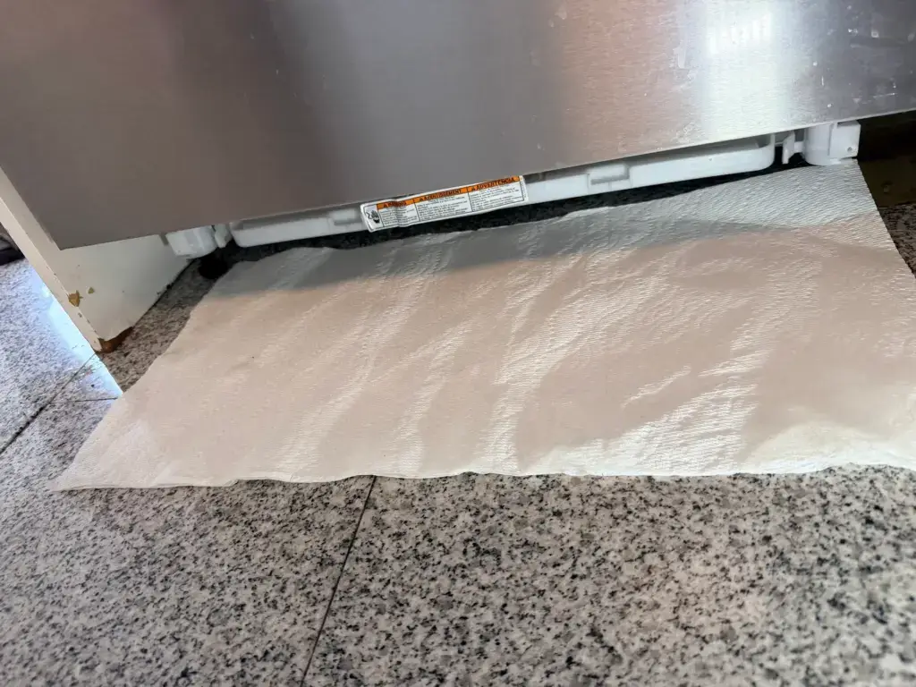 Paper towel placed under a dishwasher to trace a water leak - Appliance Forever appliance repair in Barrie, Ontario.