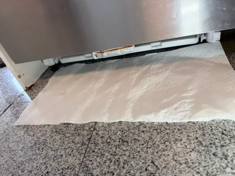 Paper towel placed under a dishwasher to trace a water leak - Appliance Forever appliance repair in Barrie, Ontario.