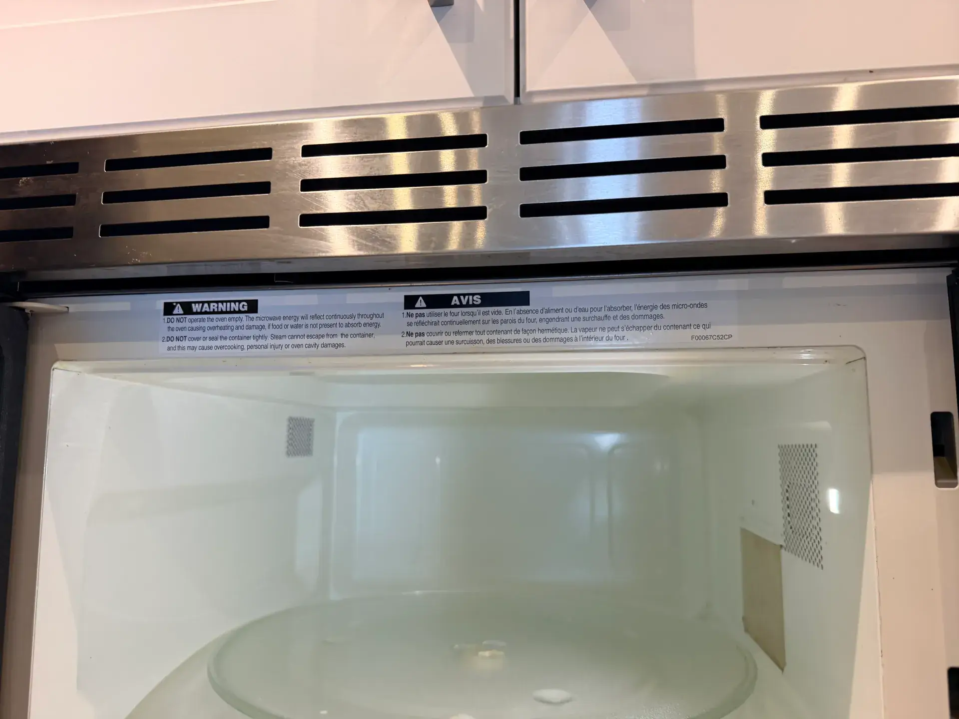 Built-in microwave with the door open showing the manufacturer warning not to operate the oven empty