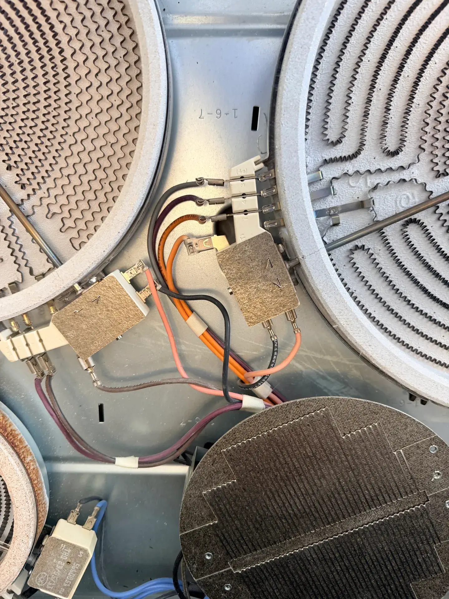 Close-up under a glass stove top: radiant heating elements, their terminal blocks and wiring, Markham
