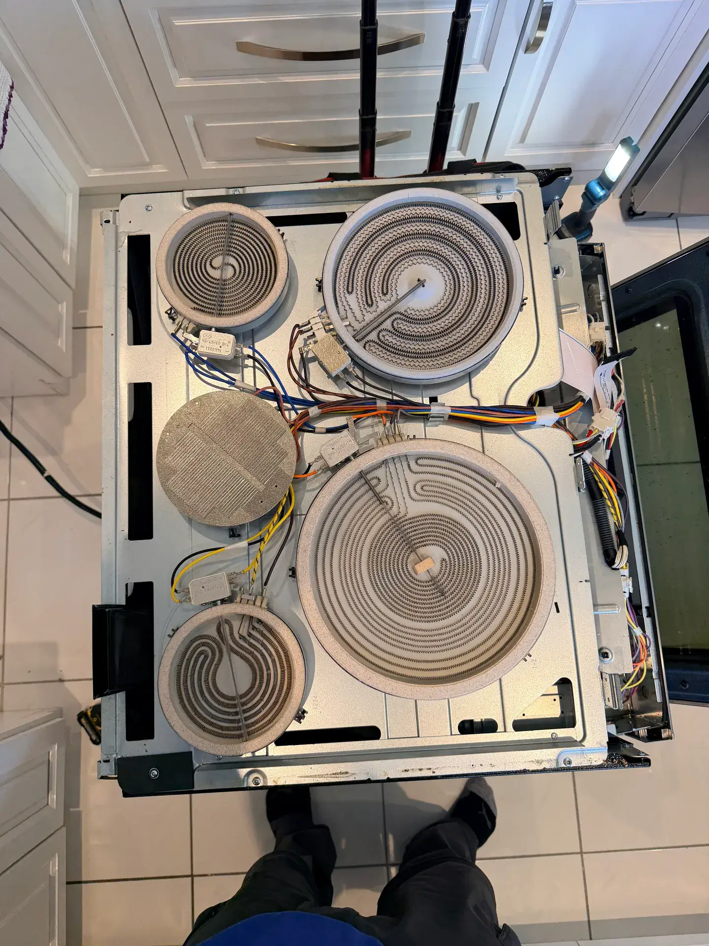 Top-down view of a range with the glass top off, showing five radiant heating elements and the wiring harness, Woodbridge