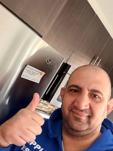 Zack, owner and head technician of Appliance Forever, giving a thumbs-up beside a stainless refrigerator